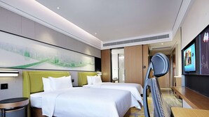 A hotel room with two beds, a TV, a desk, and a bathroom visible through an open door.