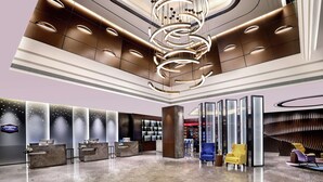 A modern hotel lobby with a reception desk, seating area, and a unique chandelier.