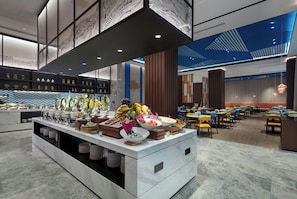 A modern hotel lobby with a buffet area, seating arrangements, and decorative ceiling patterns. - Hampton BY Hilton Qionghai Railway (QIONGHAI)