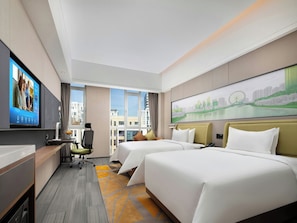 A hotel room with a large bed, a desk, a TV, and a cityscape painting.