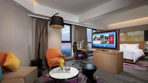 Ett modernt hotellrum med en soffa, fåtölj, skrivbord och säng.