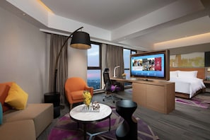 Una habitación de hotel moderna con sofá, sillón, escritorio y cama.