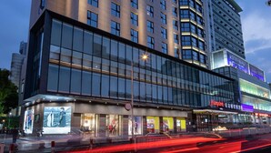 Ett hotell med en tydlig skylt med texten ”Hampton”, stora fönster och en modern arkitektonisk design.