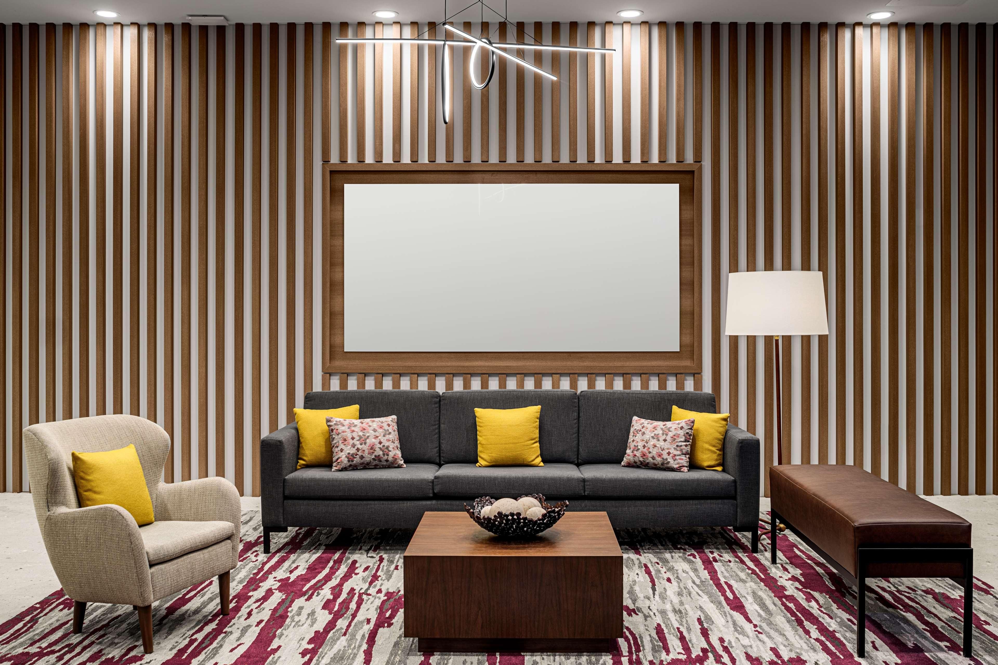A modern living room with a sofa, armchair, coffee table, and a large blank screen.