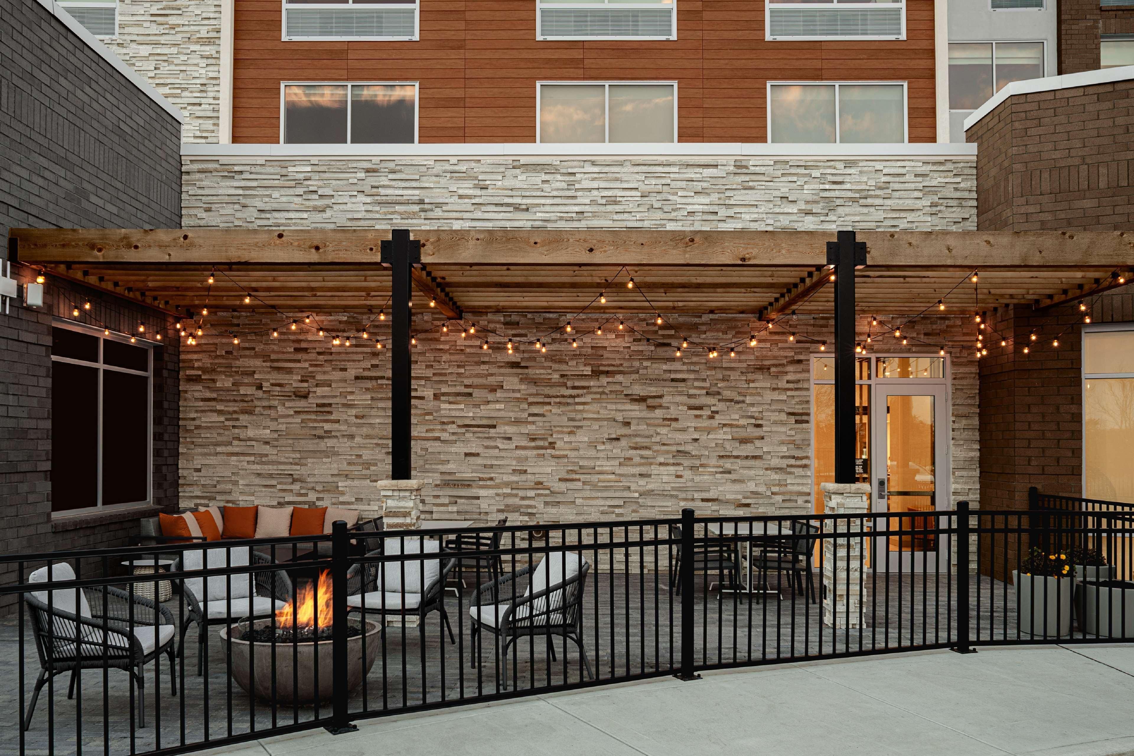 An outdoor patio area with seating, a fire pit, and string lights.