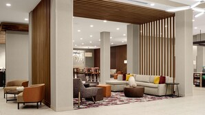 A modern hotel lobby with a sectional sofa, armchairs, and a coffee table. There are wooden slats on the walls and a patterned rug on the floor. - Hilton Garden Inn Mt.juliet (Mount Juliet)