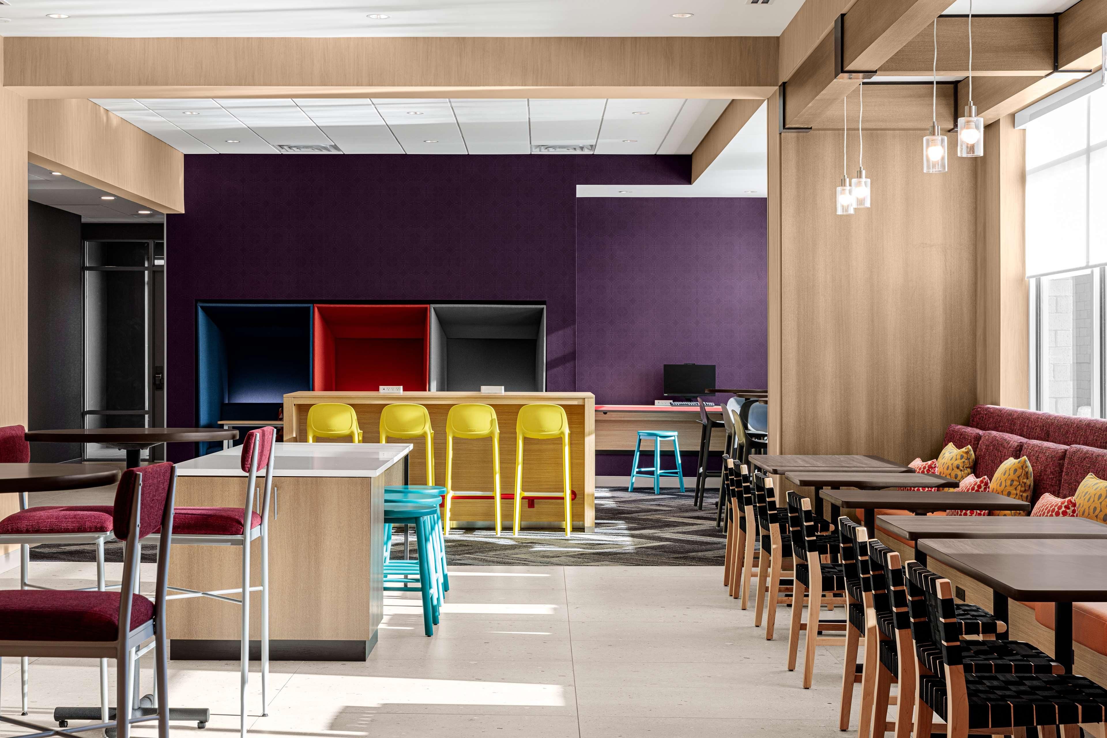 A modern dining area with multiple tables and chairs, a central bar area, and a seating area with a sofa.