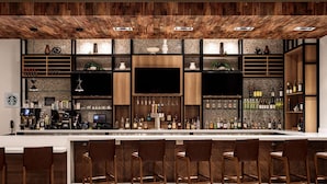 A modern bar with a wooden ceiling, a large TV screen, and a variety of liquor bottles. - Hilton Garden Inn Mt.juliet (Mount Juliet)