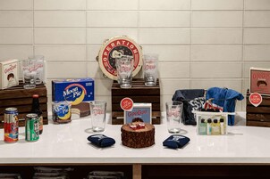Um balcão com diversos itens, incluindo latas, copos, um bolo e produtos de marca.