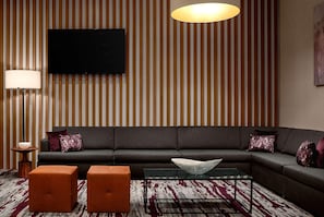 Ein modernes Wohnzimmer mit einem Ecksofa, einem Glastisch und einem Flachbildfernseher, der an einer gestreiften Wand angebracht ist.