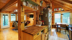 Interno di una baita in legno con angolo cottura, mobili in legno e tavolo da pranzo.