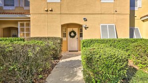 Un edificio con facciata beige, persiane bianche e una porta decorata con un'corona.