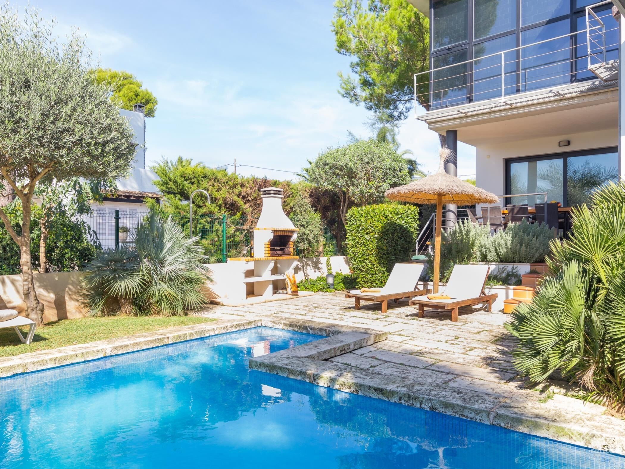 A swimming pool with lounge chairs and a barbecue area.