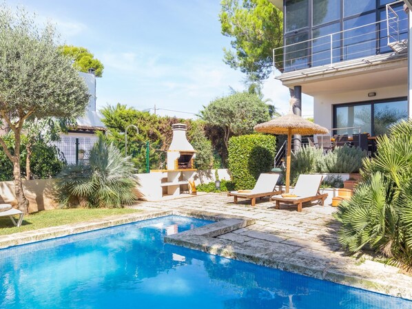 A swimming pool with lounge chairs and a barbecue area.
