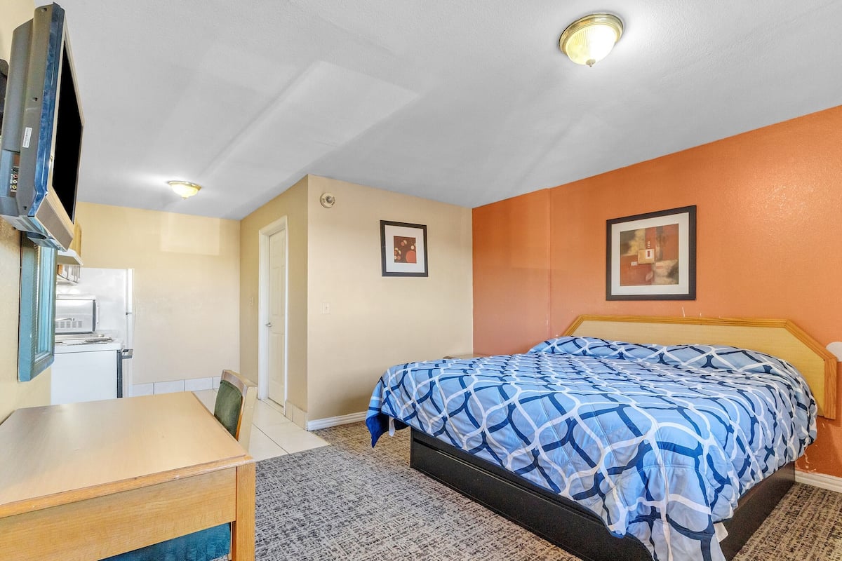 Una habitación de hotel con cama, escritorio, televisor y dos cuadros en la pared.