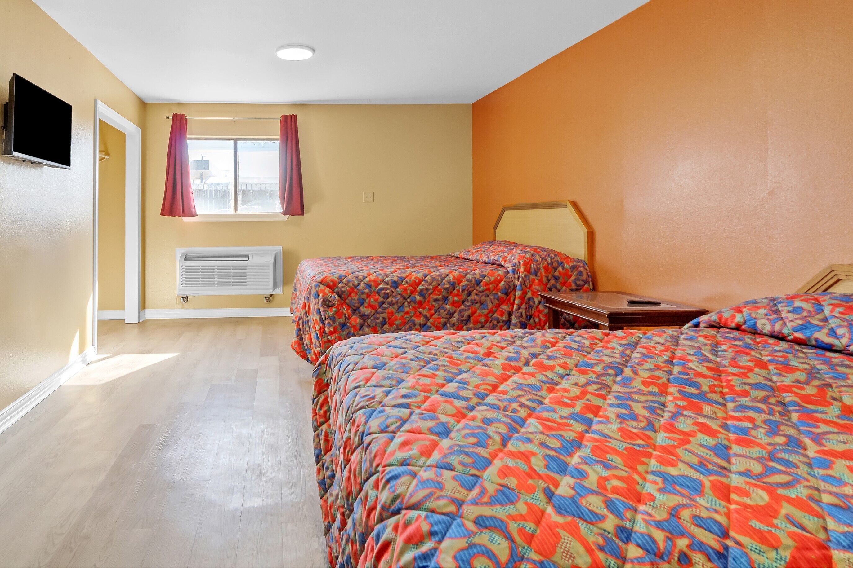 Habitación de hotel con dos camas, televisión, ventana con cortinas y calefacción.