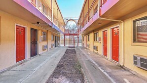 Egy folyosó, vörös ajtókkal, központi gyalogúttal, és kilátással az égre.