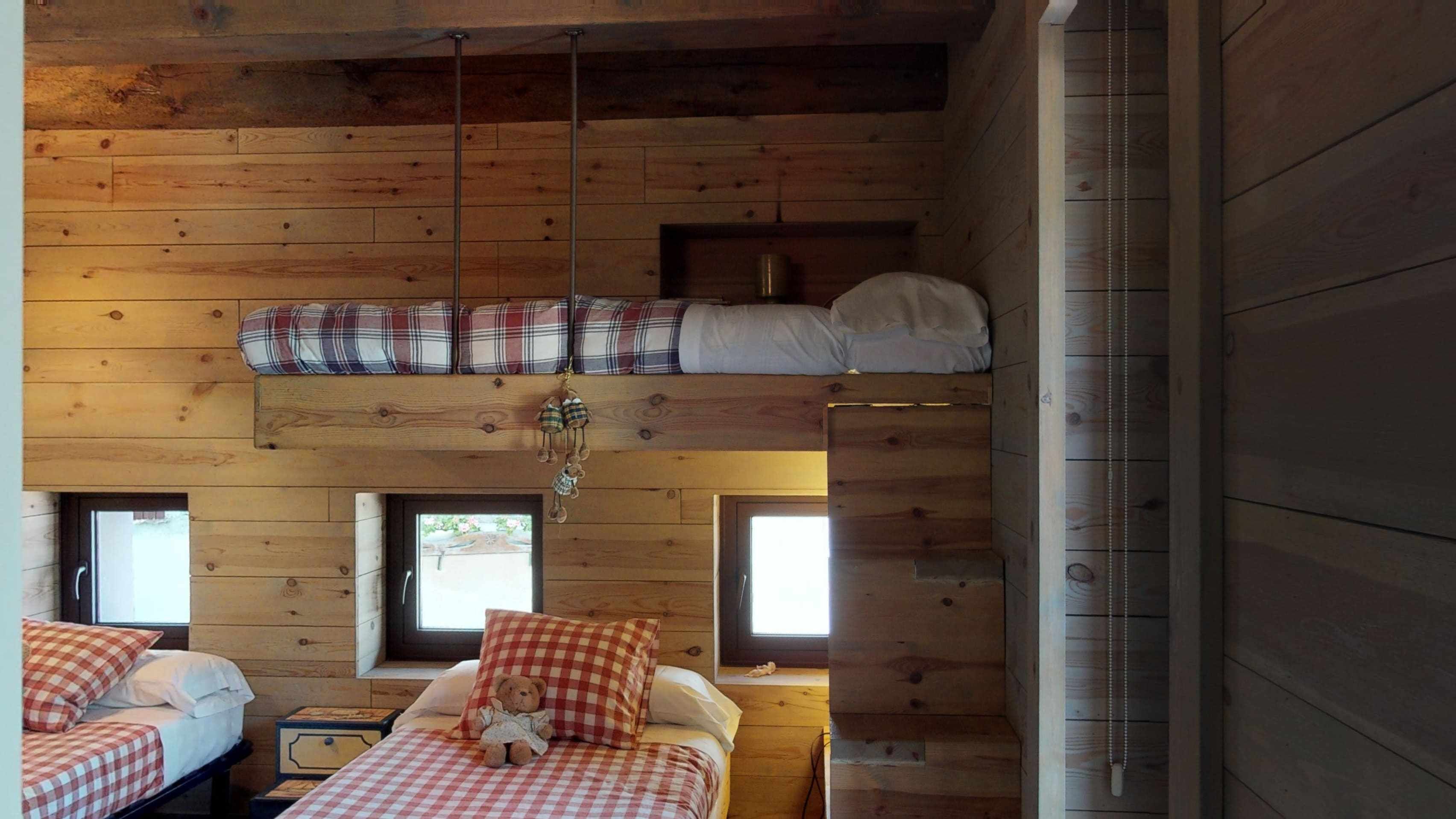 Una cabaña con dos dormitorios, cada uno con una cama y una ventana.