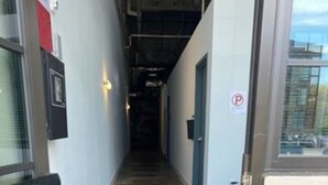 Ein Flur mit Fußmatte, einer Tür mit dem Buchstaben 'P' und einem an der Wand befestigten Gerät.