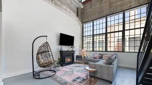 Ein modernes Wohnzimmer mit Hängesessel, Kamin, Sofa und großen Fenstern.