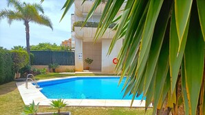 A swimming pool with a tiled deck, surrounded by grass and potted plants. - Suitur apartment with pool in Marbella beach (Marbella)