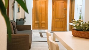 A living room with a sofa, a dining table, and a plant. There are two wooden doors and a white wall with a picture. - Suitur apartment with pool in Marbella beach (Marbella)
