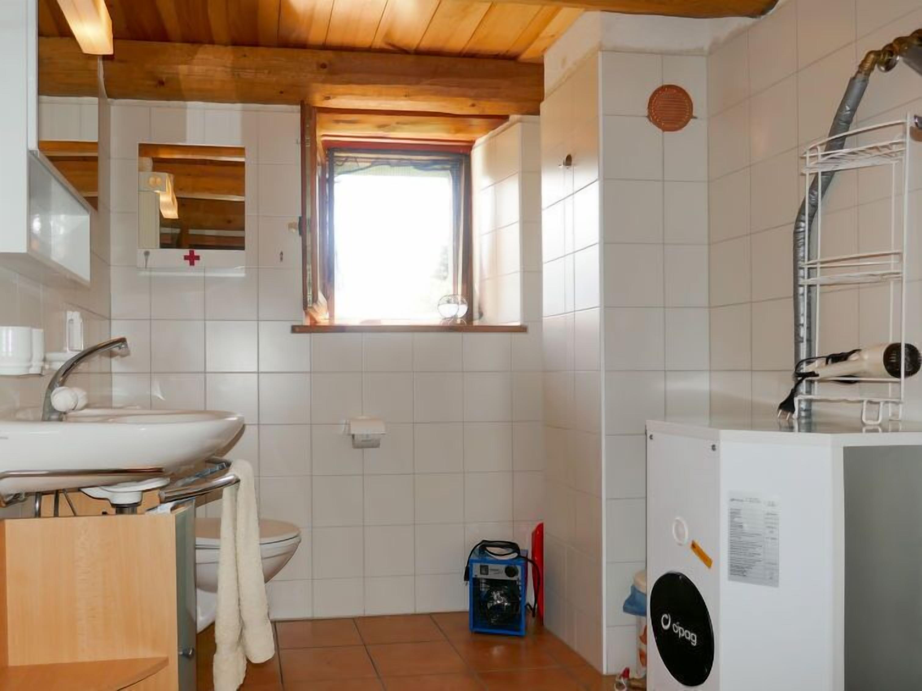 A compact bathroom with a sink, toilet, and a window.