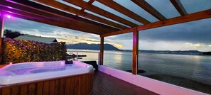 A wooden deck with a hot tub overlooking a lake, wooden pergola, and a view of mountains. - Paraiso Ribeirão da Ilha Legitimo pé na Areia (SC)