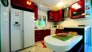 A modern kitchen with red cabinets, a white refrigerator, a microwave, and a sink. - 4 Bed Villa Sleeps 9 - Pool, Pets, Garden, Parking (Supetar)