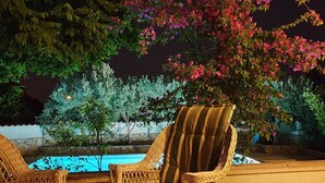 A poolside area with wicker chairs and a pool, surrounded by lush greenery and flowering plants. - 4 Bed Villa Sleeps 9 - Pool, Pets, Garden, Parking (Supetar)