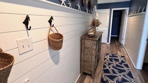 A hallway with a blue wall, white horizontal panels, starfish decorations, and a patterned rug.