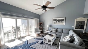 A living room with a grey sofa, a starfish rug, and a ceiling fan.