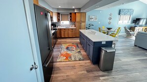 A modern kitchen with wooden cabinets, a stainless steel refrigerator, and a central island.