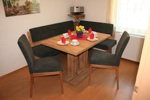 A dining table with four chairs, a vase with yellow flowers, and red napkins. - Pet-Friendly Apartment "Mark" with Mountain Views & Balcony (Biberwier)