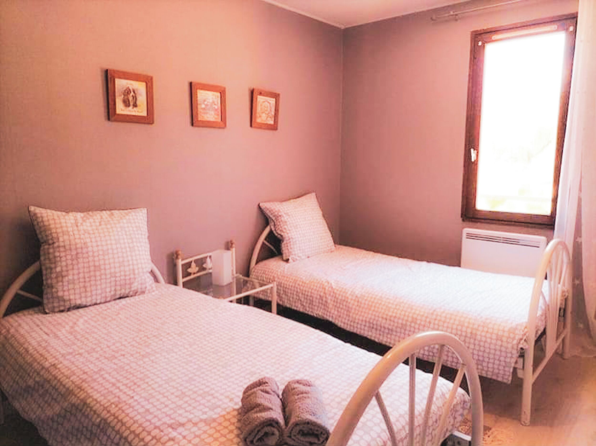 Ein kleines, gemütliches Schlafzimmer mit zwei Einzelbetten, einem Sessel und einem Fenster.