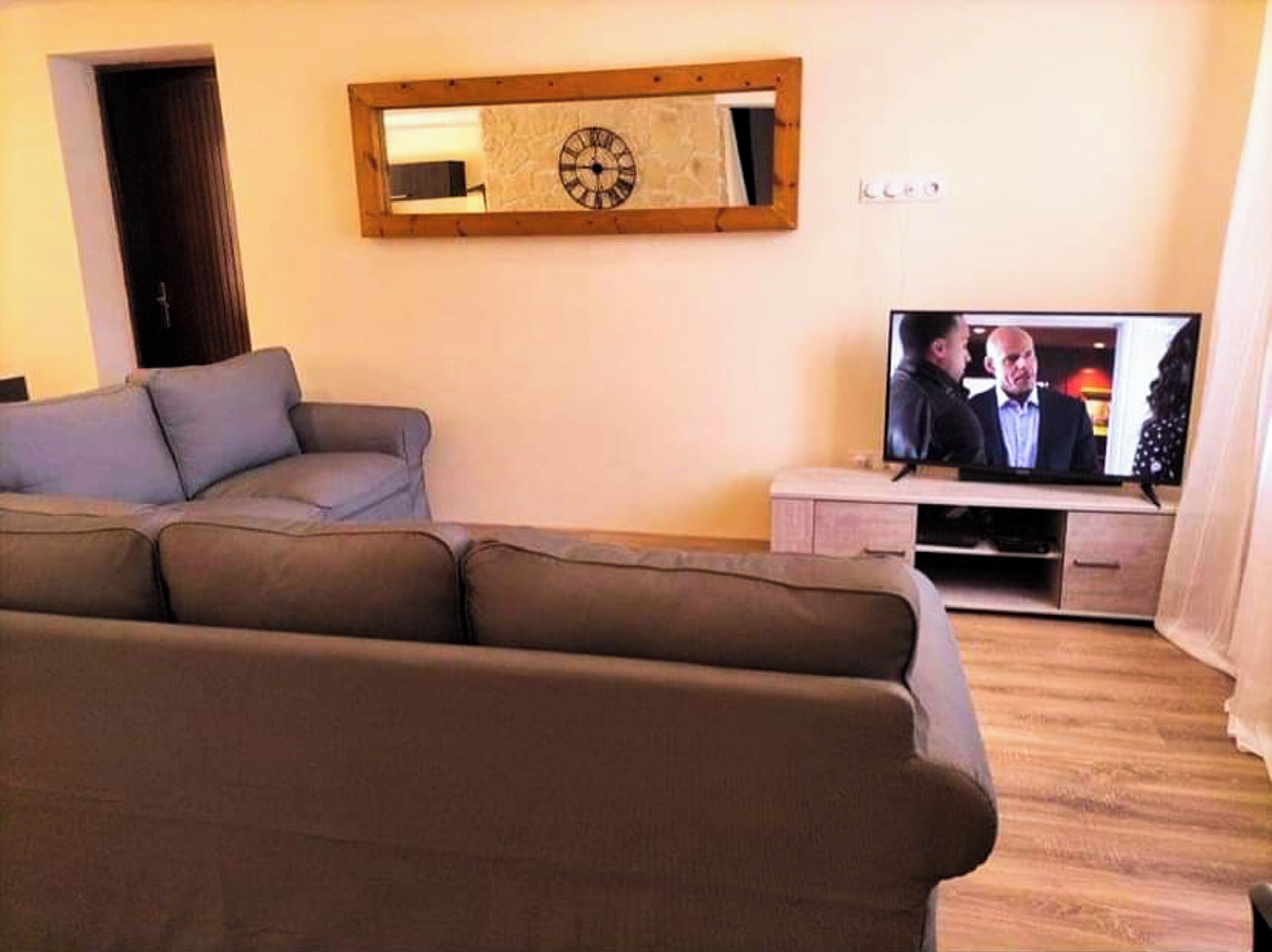 A living room with a sofa, a television, and a wooden cabinet.