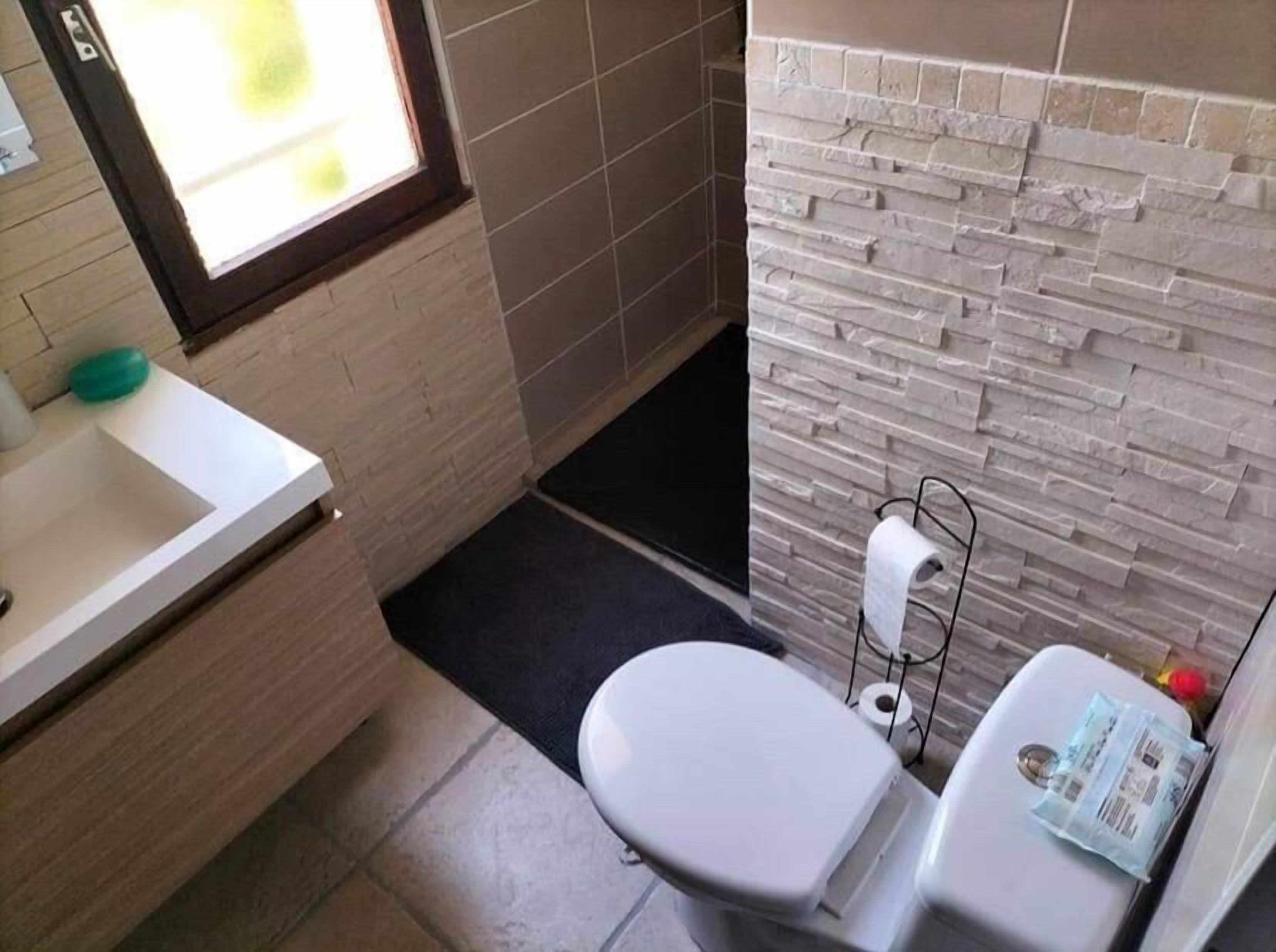 Une salle de bain avec des toilettes, un lavabo et une fenêtre.