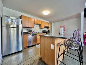 A kitchen with stainless steel appliances, wooden cabinets, a microwave, and a coffee maker.