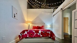 A bedroom with a bed, a lamp, and a wall-mounted picture. - 5109 Peters Cartridge Factory · ✪Kings Island Loft w/ Brewery, River, Bike trails✪ (Maineville)