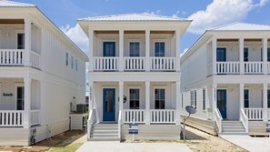 A row of white, two-story beach houses with blue doors and balconies, numbered 25087 and 25091, for rent. - Beach Side Home, Steps from the Sand. Ocean Edge 03 | A Wave From It All by Kaiser Vacation Rentals (Orange Beach)