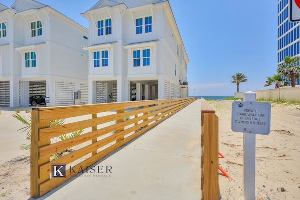Il s'agit d'une propriété située en bord de mer, avec une promenade en bois qui mène à un bâtiment blanc doté de nombreuses fenêtres. Une pancarte indique qu'il s'agit d'une promenade privée réservée aux propriétaires et aux clients des résidences situées en bord de mer.