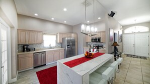 Una cocina moderna con una isla central, electrodomésticos de acero inoxidable y una alfombra roja.
