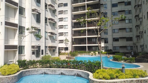 Un edificio residencial con varios balcones y una zona de piscina con una pequeña cascada.