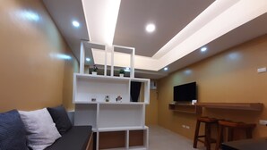 Una sala de estar moderna con un sofá, un estante blanco, un televisor y una mesa de madera.