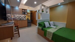 Una habitación compacta con cama, escritorio y kitchenette.