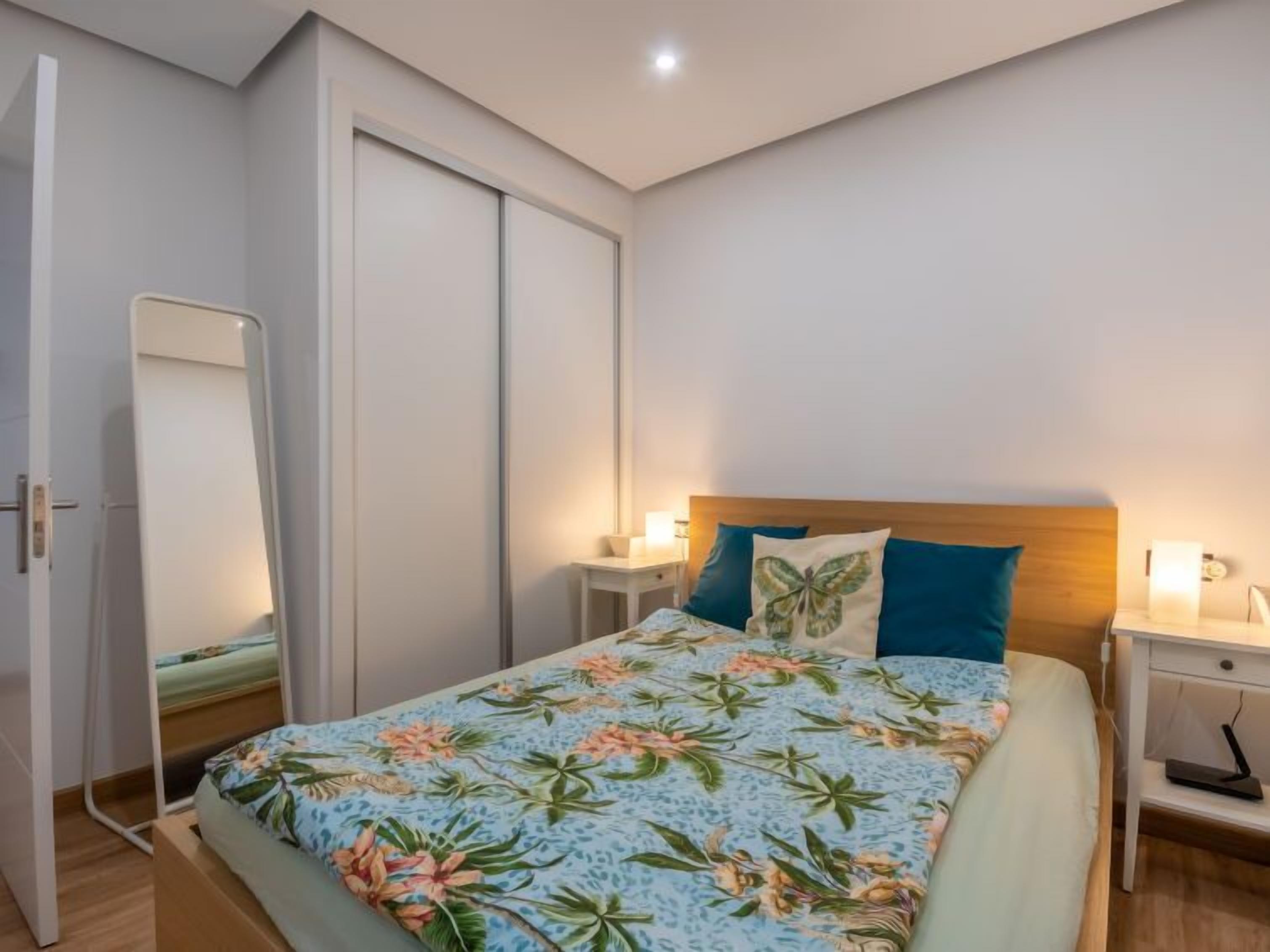 Ein Schlafzimmer mit Bett, Nachttisch, Spiegel und Kleiderschrank.