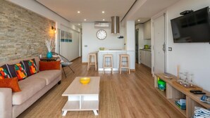 Una sala de estar moderna con un sofá, una mesa de centro y una zona de cocina con un juego de comedor.