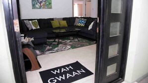 A living room with a black sofa, a glass coffee table, and a patterned rug. - Elevated Experience at the Bromptons (Kingston)
