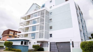 A multi-story residential building with balconies, a garage, and a gated entrance. - Elevated Experience at the Bromptons (Kingston)