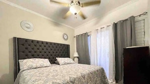 A bedroom with a tufted headboard, patterned bedspread, and a ceiling fan. - Elevated Experience at the Bromptons (Kingston)